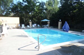 Una piscina al aire libre de temporada, sillones reclinables de piscina