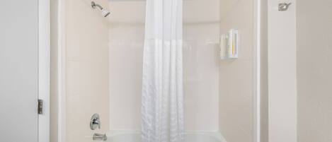 Un bagno con una vasca, una tenda da doccia e un sostegno.