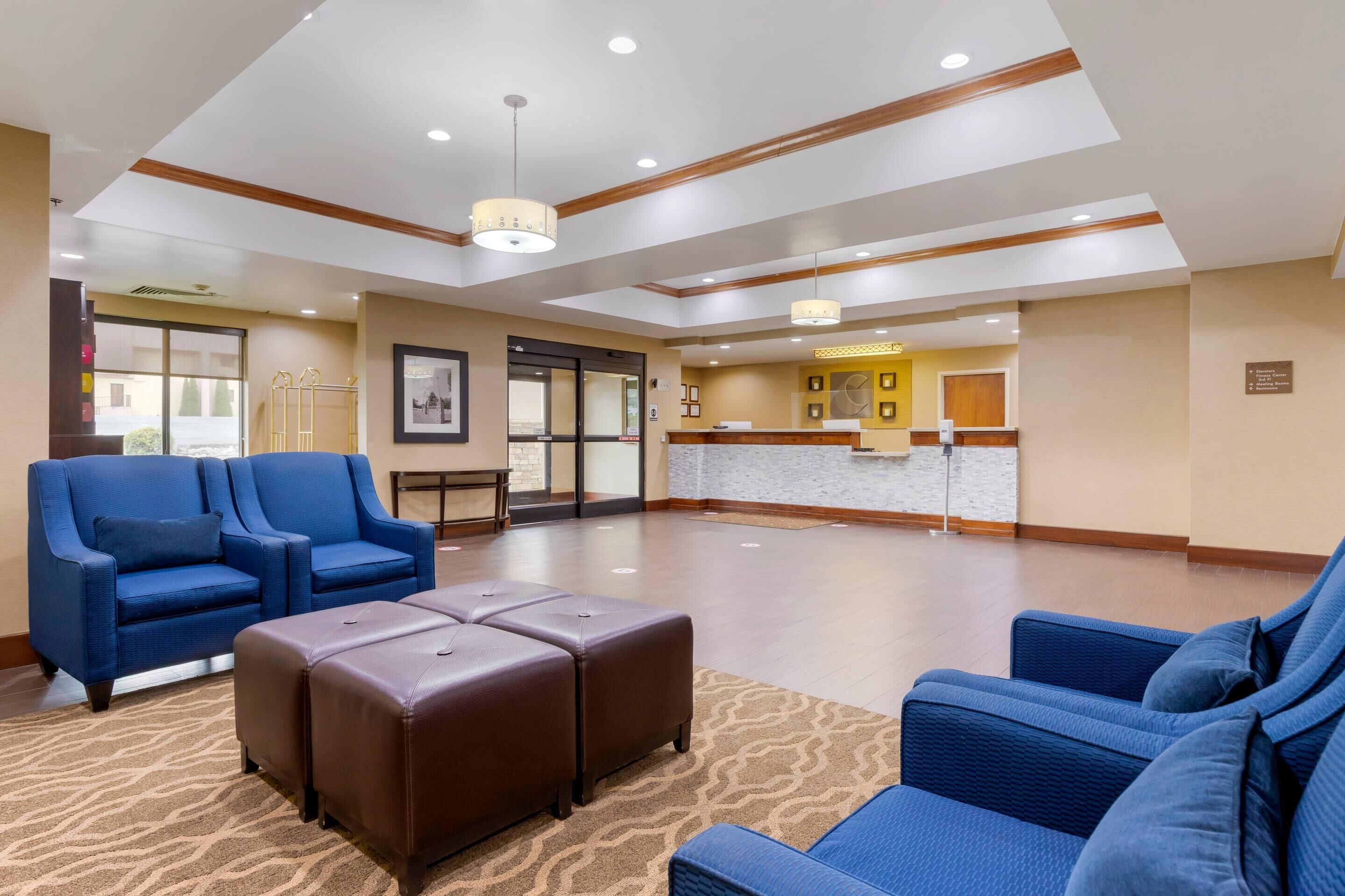 A hotel lobby with blue seating, a reception desk, and a patterned carpet.