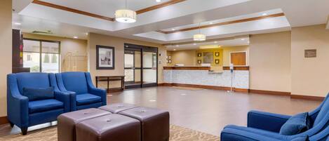A hotel lobby with blue seating, a reception desk, and a patterned carpet.