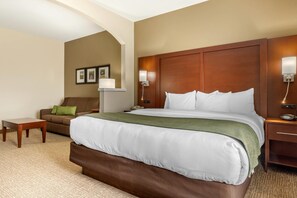 Een hotelkamer met een groot bed, een bank, een kleine tafel en een nachtkastje met een lamp.