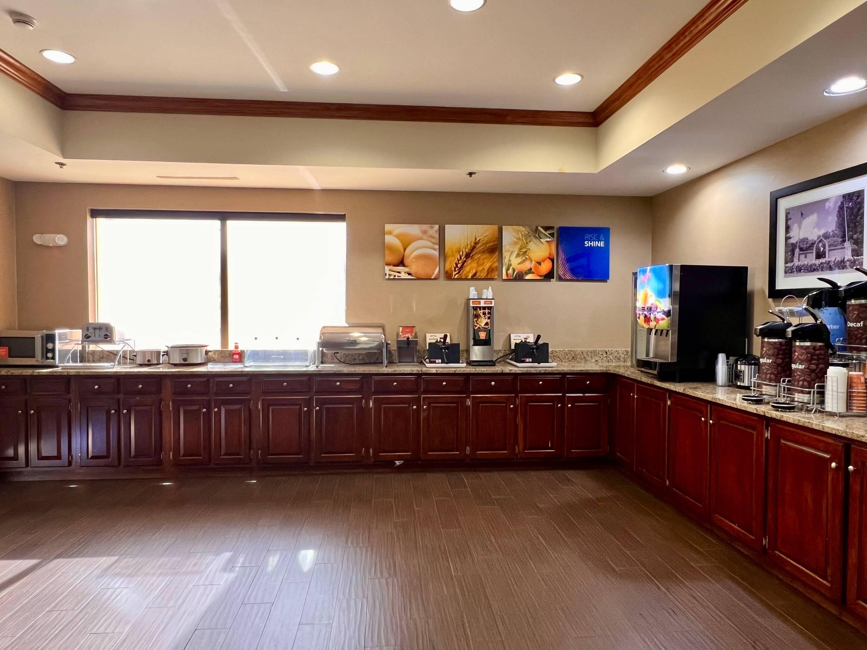 A spacious kitchen with wooden cabinets, a large window, and various appliances including a coffee machine and a toaster.