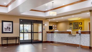 Un hall de hotel con mostrador de recepción, un banco y una puerta que da al exterior.