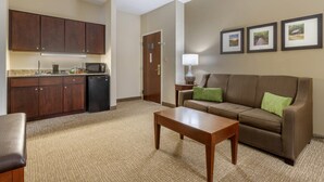 Un espacio habitable compacto con kitchenette, un sofá, una mesa de centro y cuadros en la pared.
