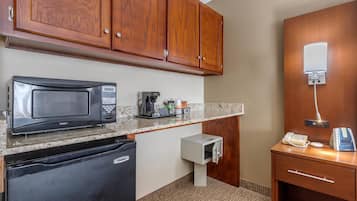 A compact kitchen with a microwave, coffee maker, and a refrigerator.