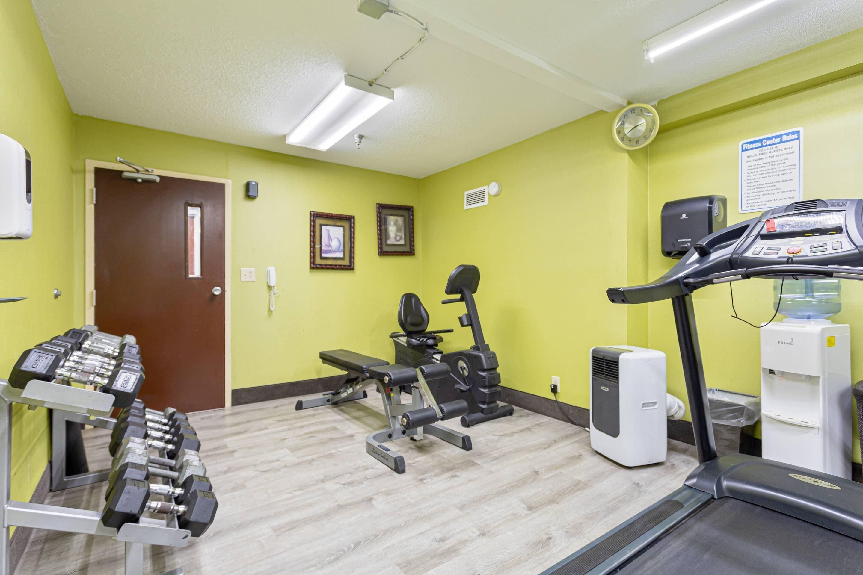 A fitness center with exercise equipment, a treadmill, and a water dispenser.