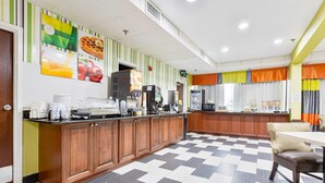 A hotel kitchen with a checkered floor, wooden cabinets, and a coffee station. - Quality Inn Prattville I-65 (Prattville)