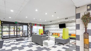 A lobby with a checkered floor, grey sofas, a white coffee table, and a decorative vase. - Quality Inn Prattville I-65 (Prattville)