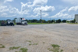 Guests can park their vehicles in this open area surrounded by a grassy field and trees.