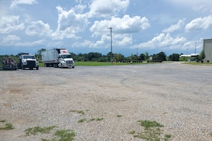 Guests can park their vehicles in this open area surrounded by a grassy field and trees.