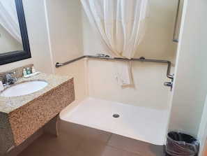 Bathroom features a sink, mirror, and bathtub with grab bar for safety.