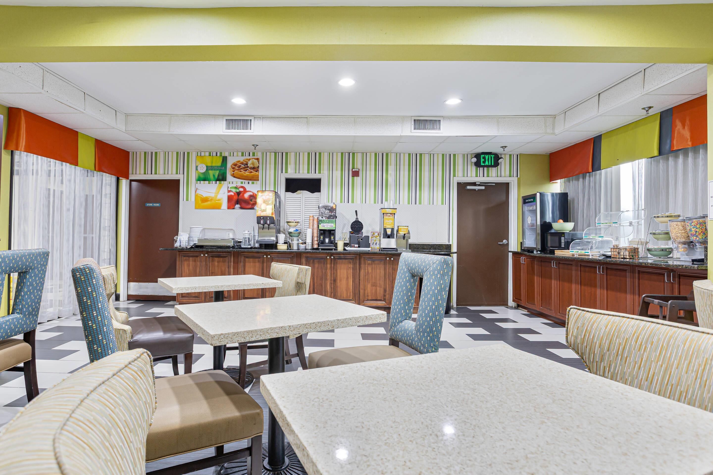 A restaurant with a counter, tables, and chairs.