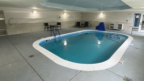 An indoor swimming pool with a tiled floor, a blue pool, and a ceiling with a skylight.