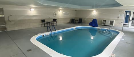 An indoor swimming pool with a tiled floor, a blue pool, and a ceiling with a skylight.