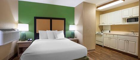Ein Hotelzimmer mit Bett, Nachttischlampen, Telefon, Mikrowelle und einer Küchenzeile.