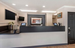 A reception desk with a flat-screen TV, a digital display, and a framed welcome sign. - Extended Stay America Suites Denver Tech Ctr S Inverness (Englewood)