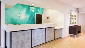 A reception area with a modern design, featuring a large mirror, a reception desk, and a small seating area with a cabinet. - SpringHill Suites Phoenix North (Phoenix)