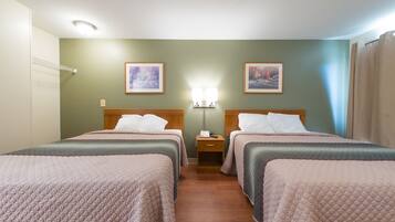 A hotel room with two beds, a nightstand, a lamp, and two framed pictures on the wall.