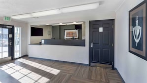 A reception area with a reception desk, a 'WELCOME' sign, an exit sign, and a door. - Extended Stay America Select Suites Denver Cherry Creek (Glendale)
