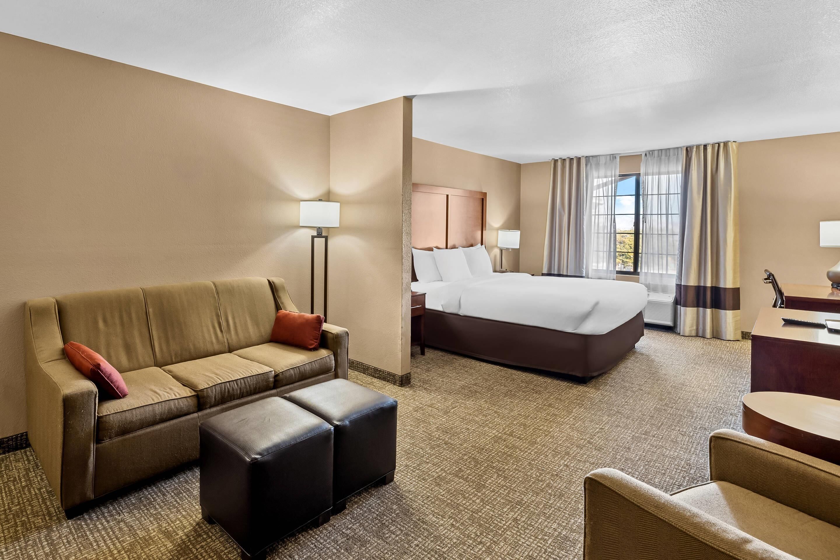 A hotel room with a bed, a sofa, a desk, and a chair.