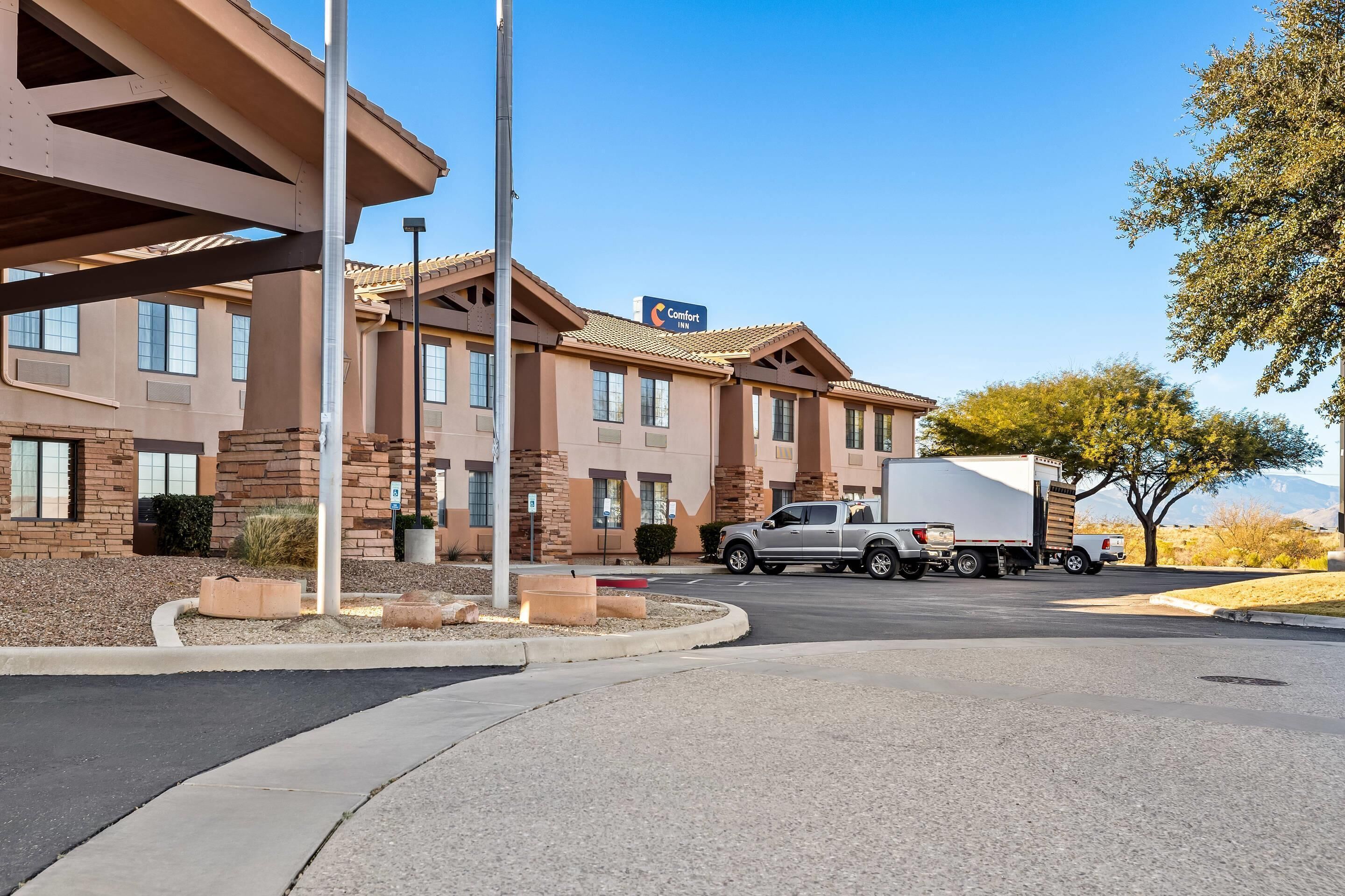 A hotel with a brick facade, a large truck parked in front, and a clear blue sky.
