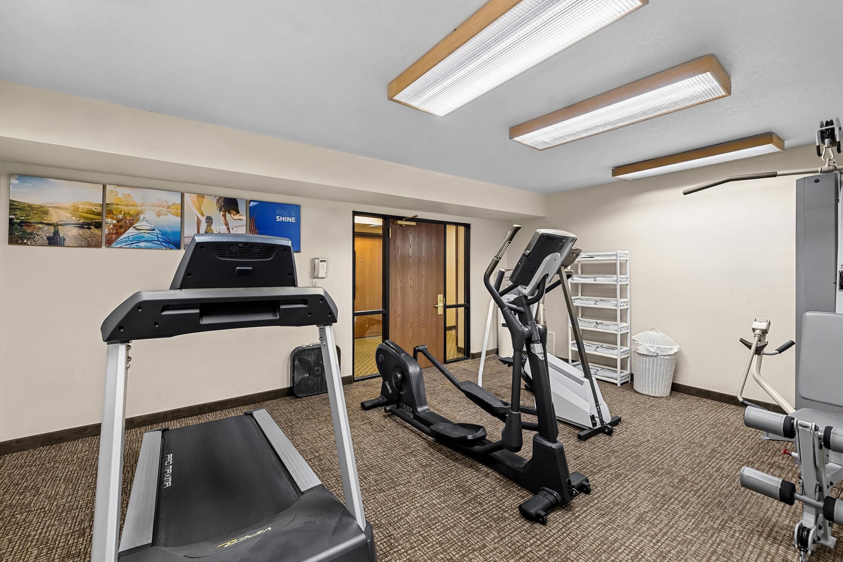 A fitness room with a treadmill, elliptical, and exercise bike.