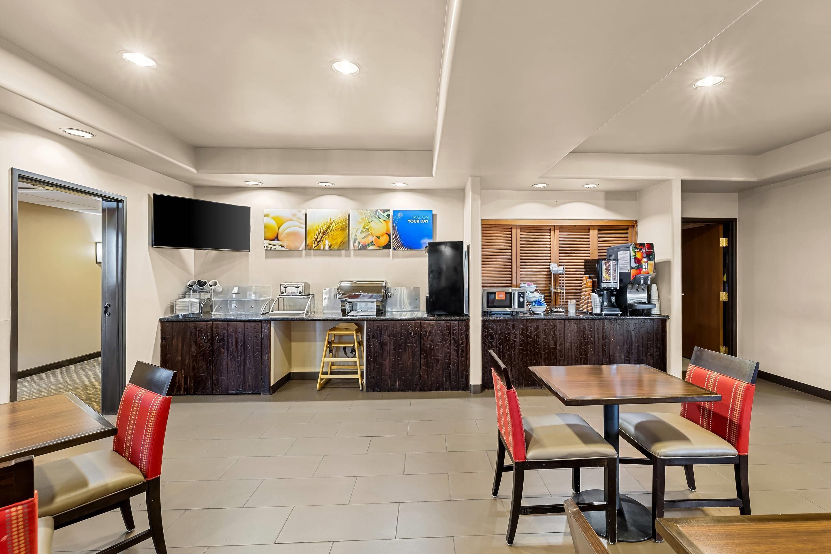 Un espace repas d’hôtel comprenant un comptoir, des sièges et un téléviseur.