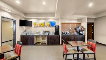 Un espace repas d’hôtel comprenant un comptoir, des sièges et un téléviseur.