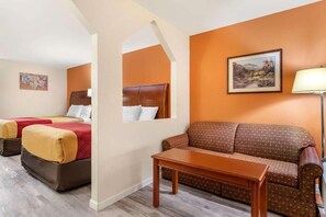 A hotel room with two beds, a sofa, a table, and a painting on the wall.