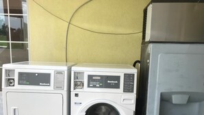 A front-loading white washer and dryer unit with a control panel, next to a water dispenser. - Kings Inn (LaFayette)
