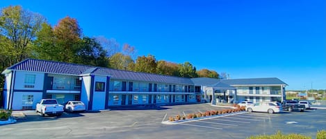 Un motel composé d’un bâtiment à deux étages, d’un parking et surplombant un ciel d’un bleu limpide.
