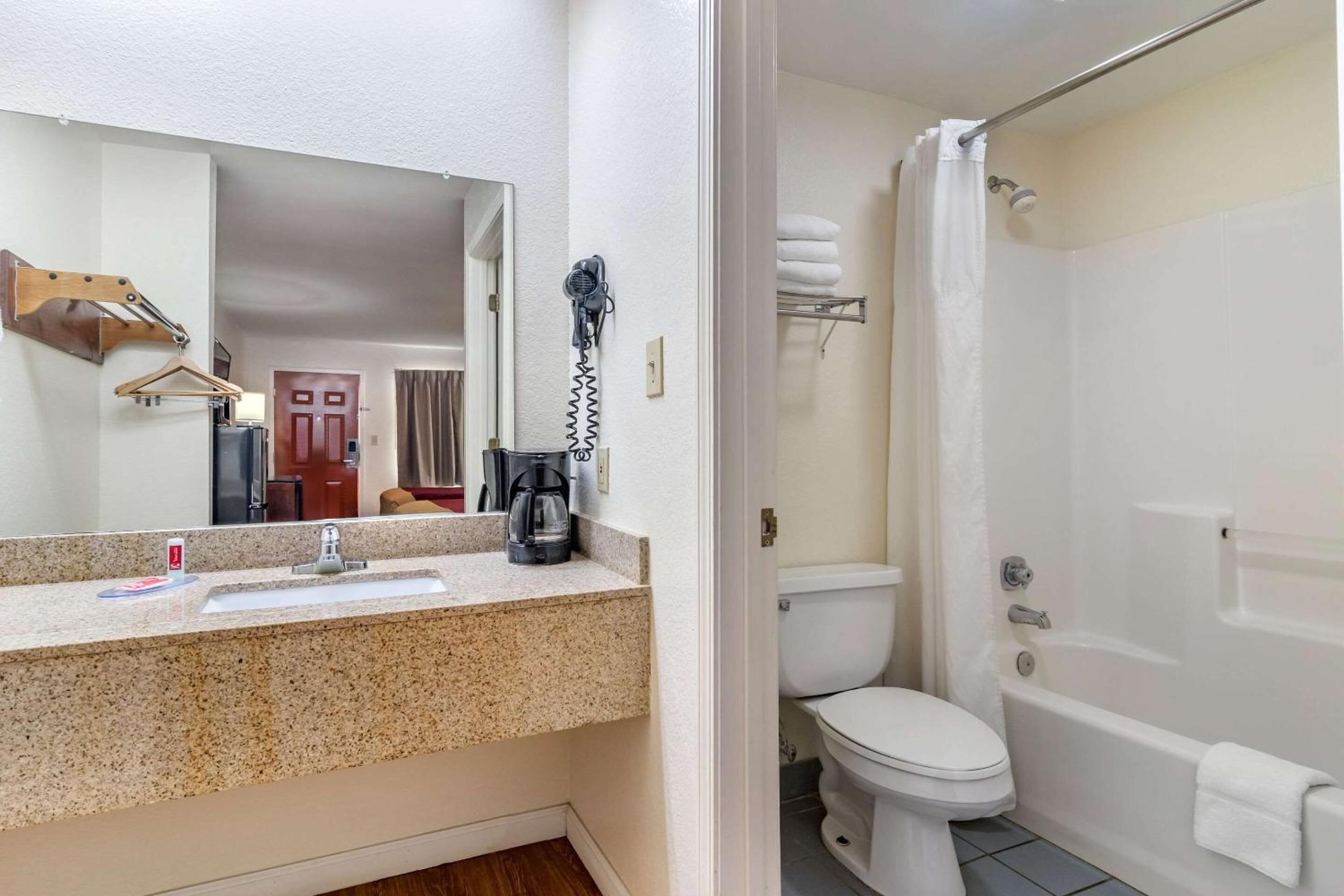 Une salle de bain équipée d’un lavabo, d’un miroir, d’un sèche-cheveux, de toilettes et d’une baignoire.