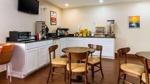 A compact kitchen with white cabinets, a microwave, a coffee machine, and a TV mounted on the wall. - Kings Inn (LaFayette)