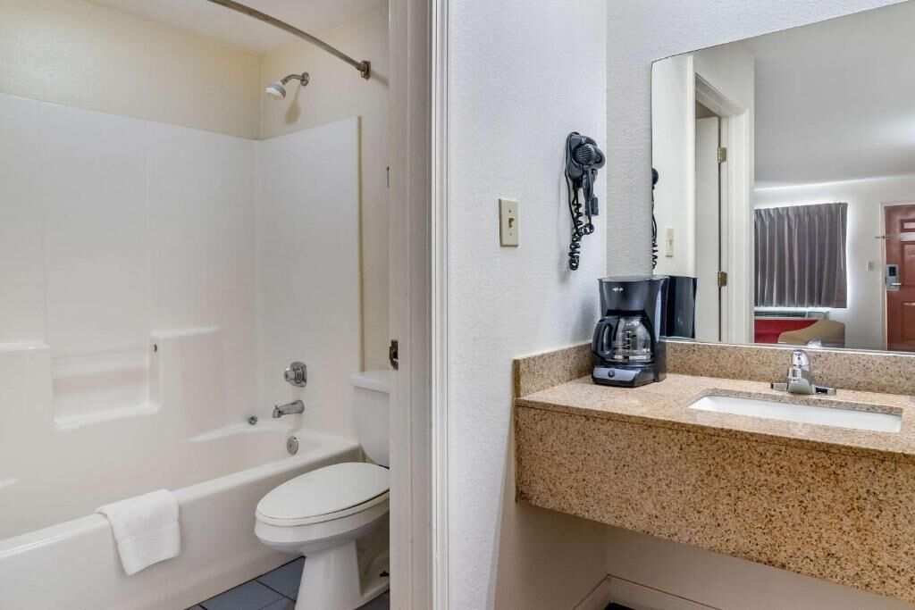 Ein Badezimmer mit Badewanne, Toilette und Waschbecken, inklusive Kaffeemaschine.