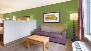 A room with a green wall, a purple sofa, a wooden table, a reception desk, and a framed picture. - Extended Stay America Suites Washington DC Germantown Town C (Germantown)
