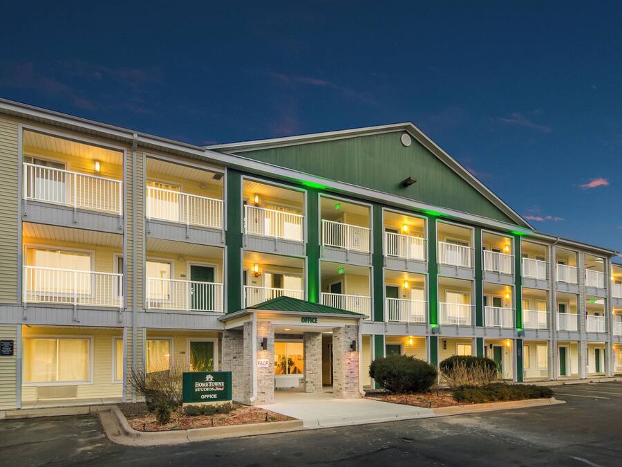 A multi-story hotel with a green roof, multiple balconies, and a sign indicating an office.