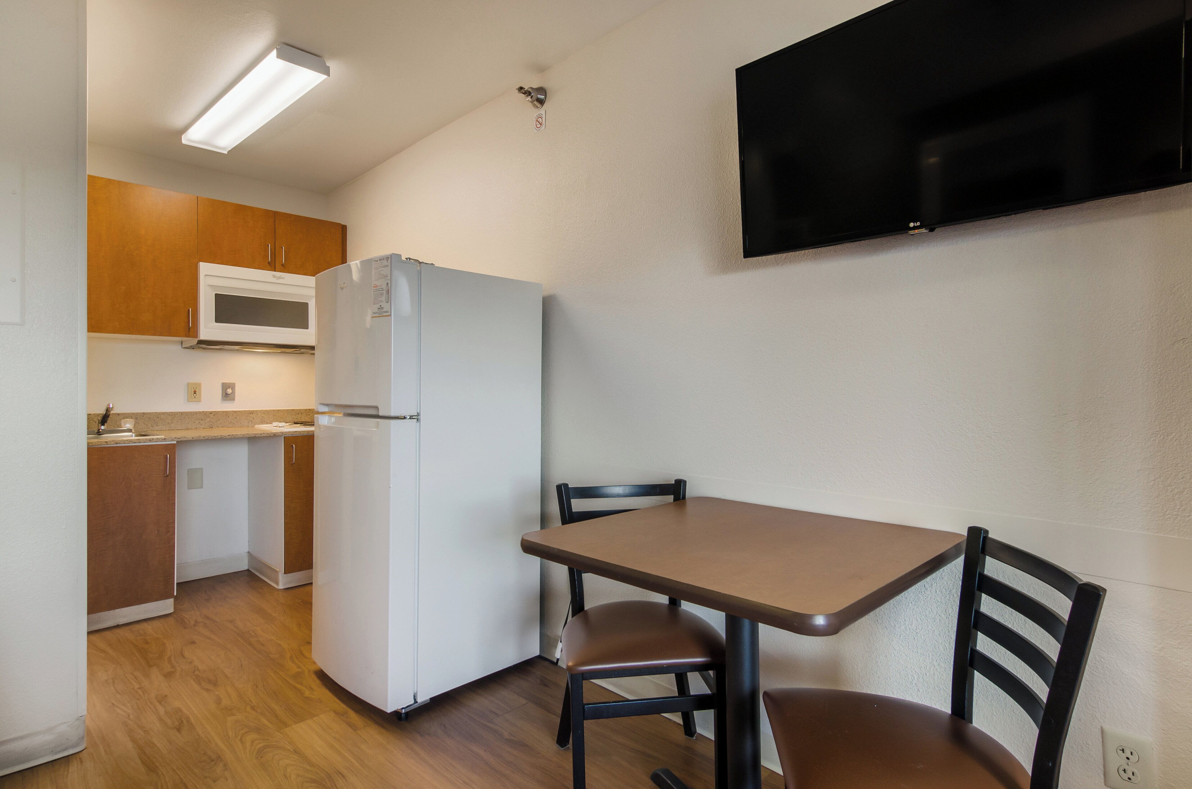 A compact kitchen with a refrigerator, microwave, and wooden cabinets.