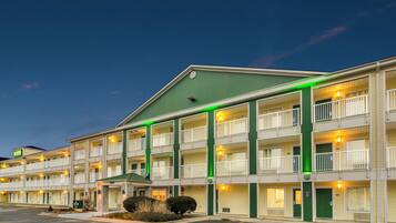 A multi-story motel with a green roof, multiple balconies, and a parking lot.