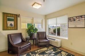 Una habitación con dos sillones de cuero, una mesita con una planta, un radiador y un ventanal con vistas.