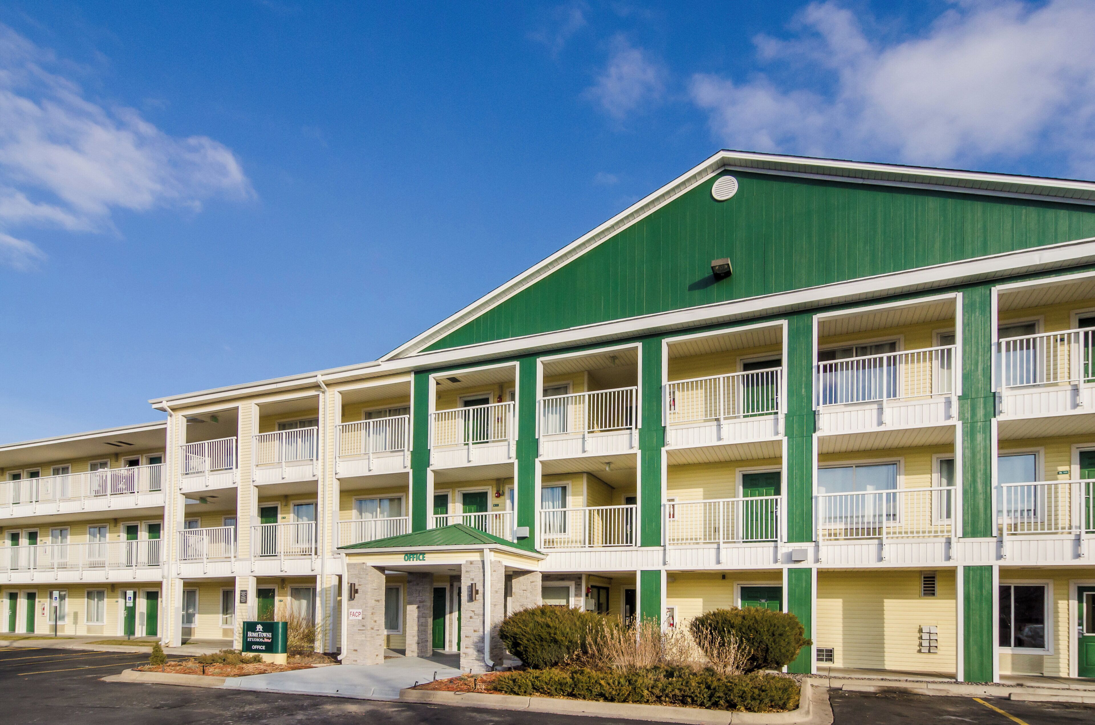 Een motel met meerdere verdiepingen, een groen dak en witte buitenmuren, met balkons en een centrale ingang.