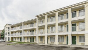 A multi-story motel with balconies, a parking lot, and a street view. - HomeTowne Studios By Red Roof Denver - Glendale/ Cherry Creek (Glendale)