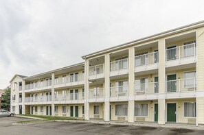Un motel de varios pisos con balcones, estacionamiento y vista a la calle.