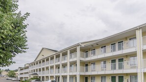 A multi-story motel with balconies, a parking lot, and a grassy area. - HomeTowne Studios By Red Roof Denver - Glendale/ Cherry Creek (Glendale)