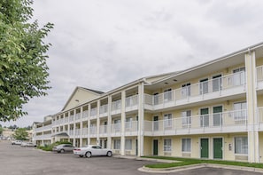 Un motel de varios pisos con balcones, estacionamiento y un área con césped.