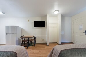 Ett litet, rent rum med en säng, ett skrivbord, en stol, en tv och en garderob.
