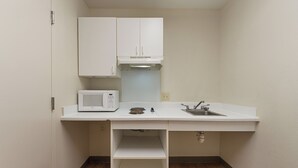 Una piccola cucina componibile con un forno a microonde, un lavandino e un armadietto.