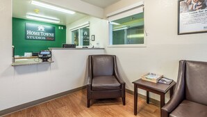 Un'area reception con parete verde, una scrivania, una sedia, un tavolino con una rivista e un quadro appeso al muro.