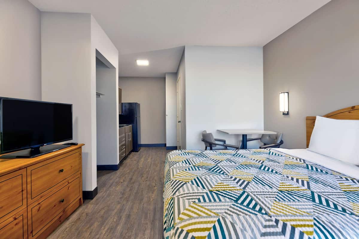 Een hotelkamer met een bed, een televisie op een houten dressoir, een bureau met stoel en een kleine tafel met stoel.