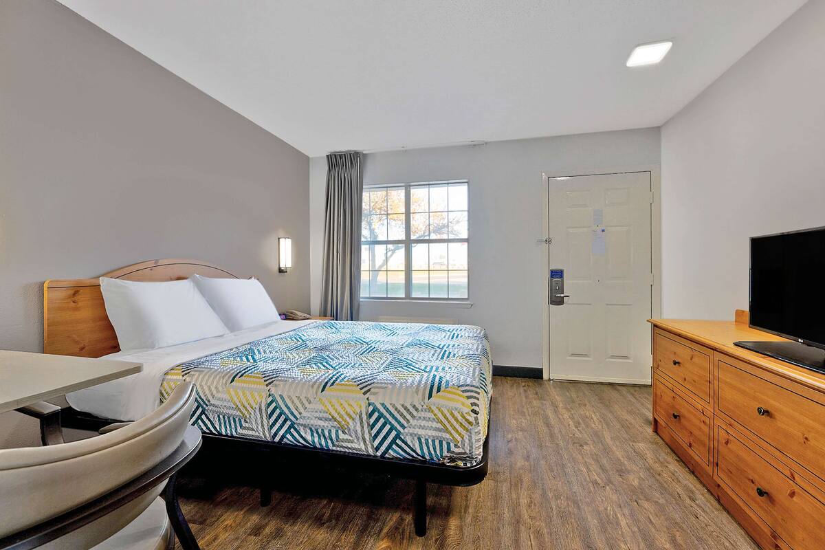 Een hotelkamer met een bed, een bureau, een televisie en een kledingkast.