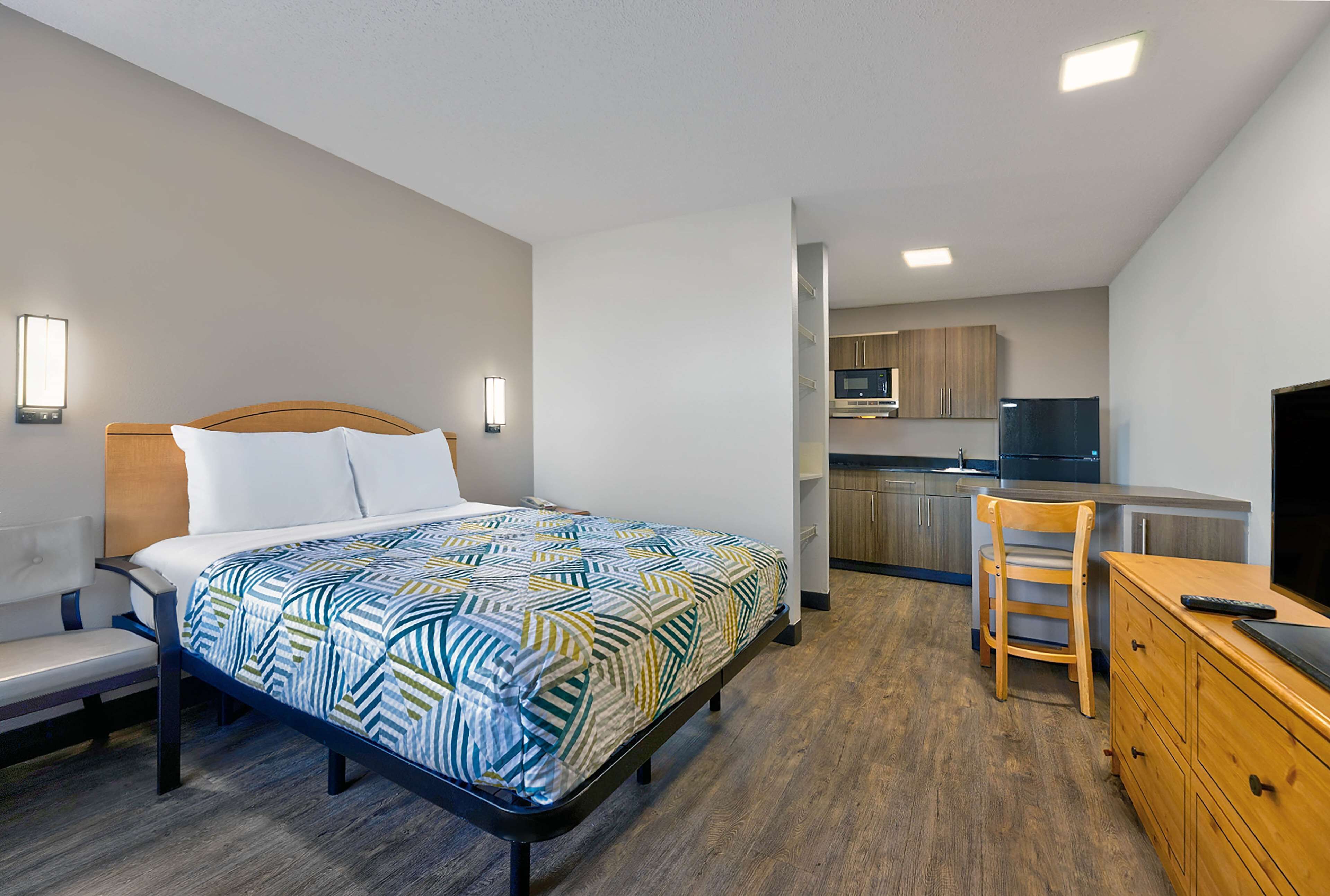 A bedroom with a bed, bedside table, and a small desk area with a chair.